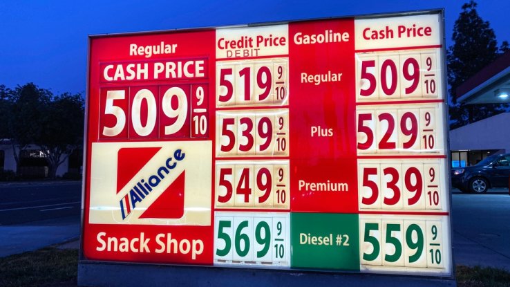 An outdoor sign announces the cost of gas at a station. All of the prices are over $5 per gallon.